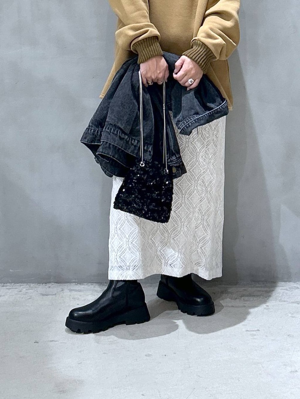 ブラック系のブーツ、ブラック系のデニムジャケット、ホワイト系のスカートを着用したレディースの秋コーディネートの3枚目の写真