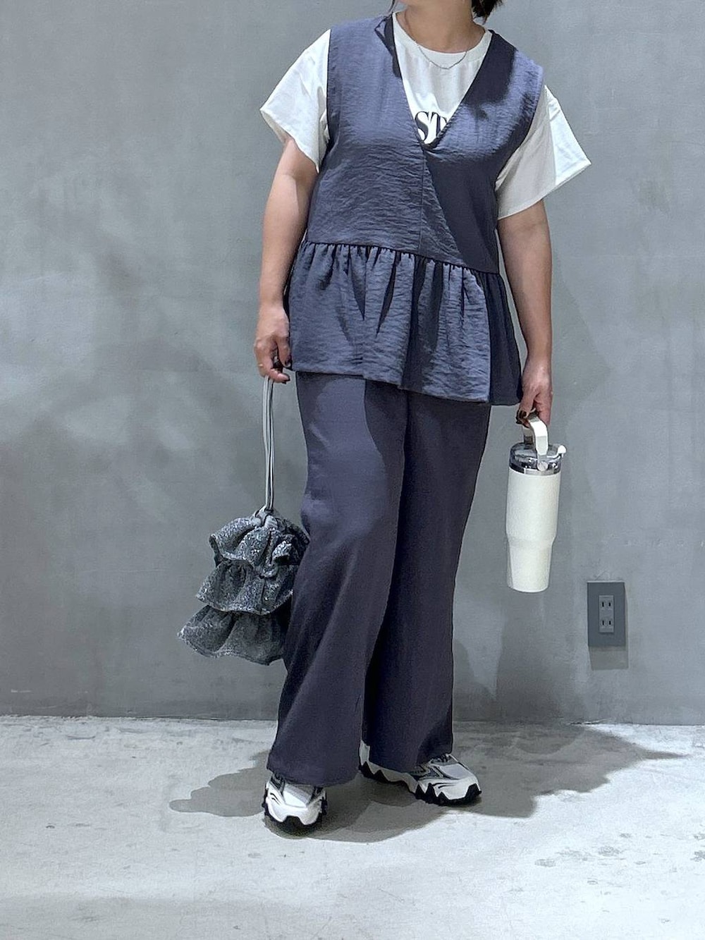 シルバー系のショルダーバッグ、ホワイト系のスニーカー、グレー系のその他パンツを着用したレディースの夏コーディネートの3枚目の写真