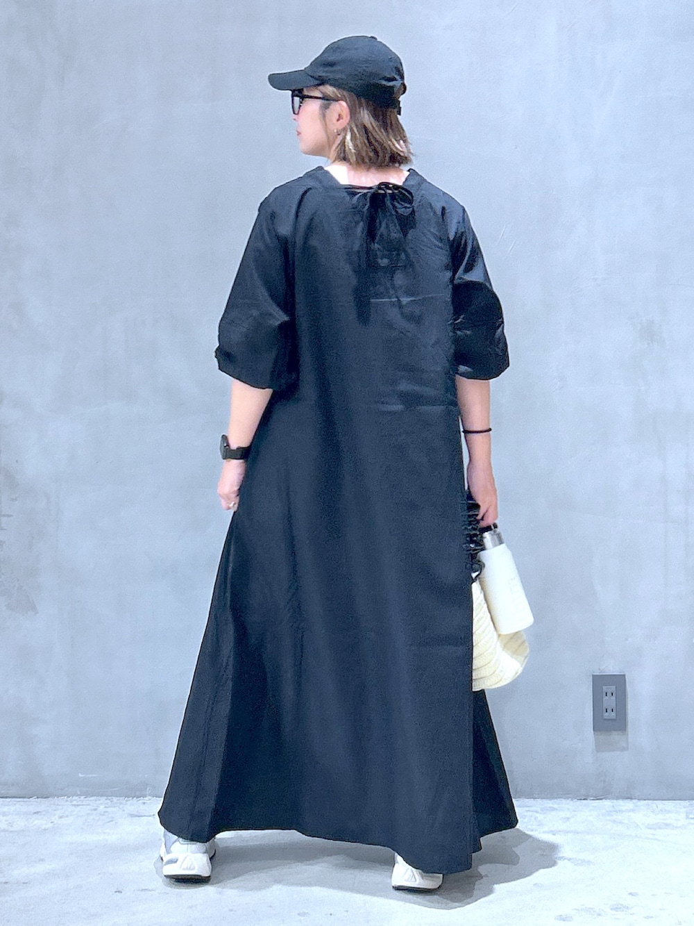 ブラック系のワンピース、グレー系のスニーカー、ホワイト系のショルダーバッグを着用したレディースの夏コーディネートの2枚目の写真