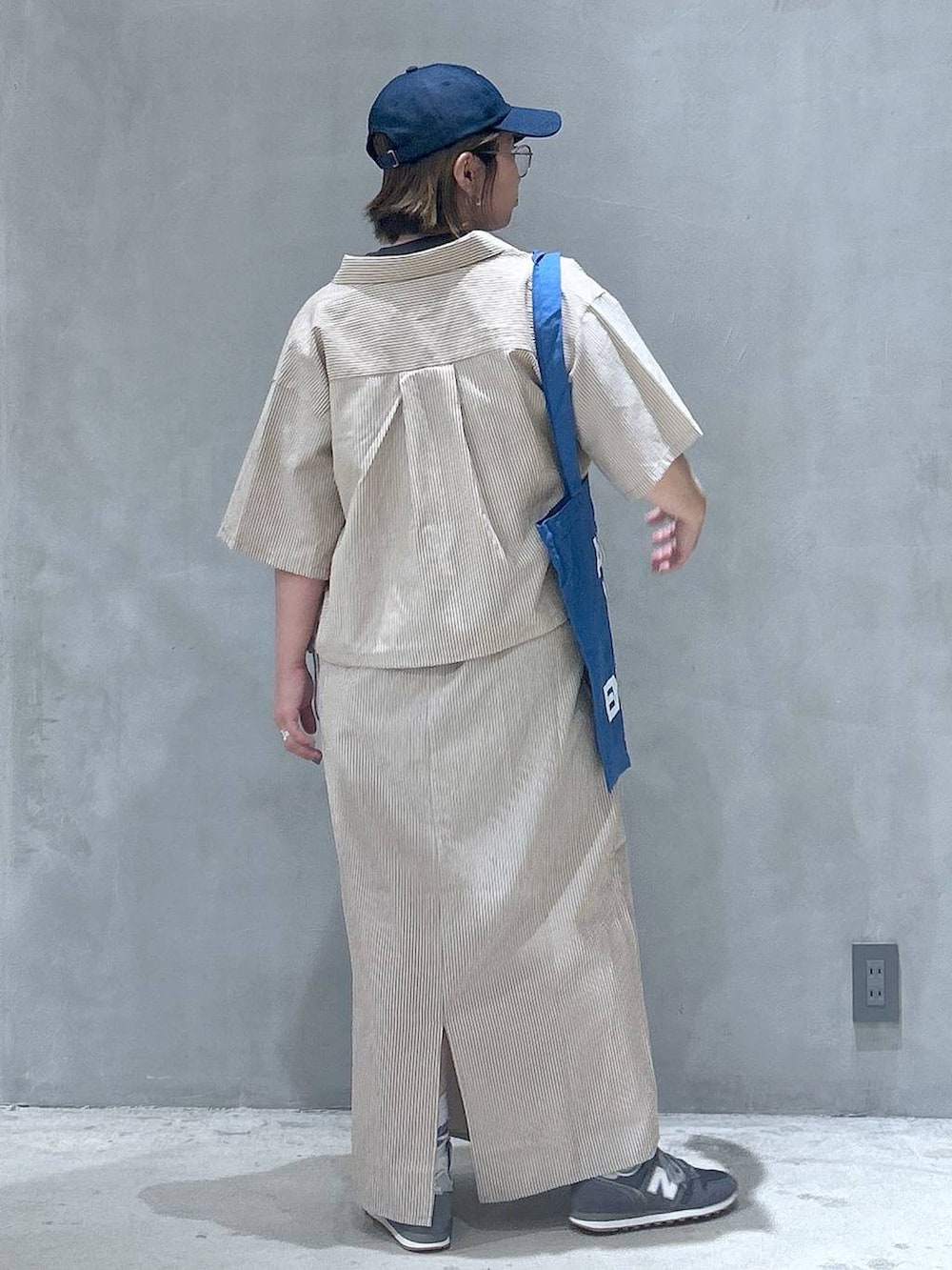 グレー系のスニーカー、ブルー系のトートバッグ、グレー系のTシャツ/カットソーを着用したレディースの春コーディネートの2枚目の写真