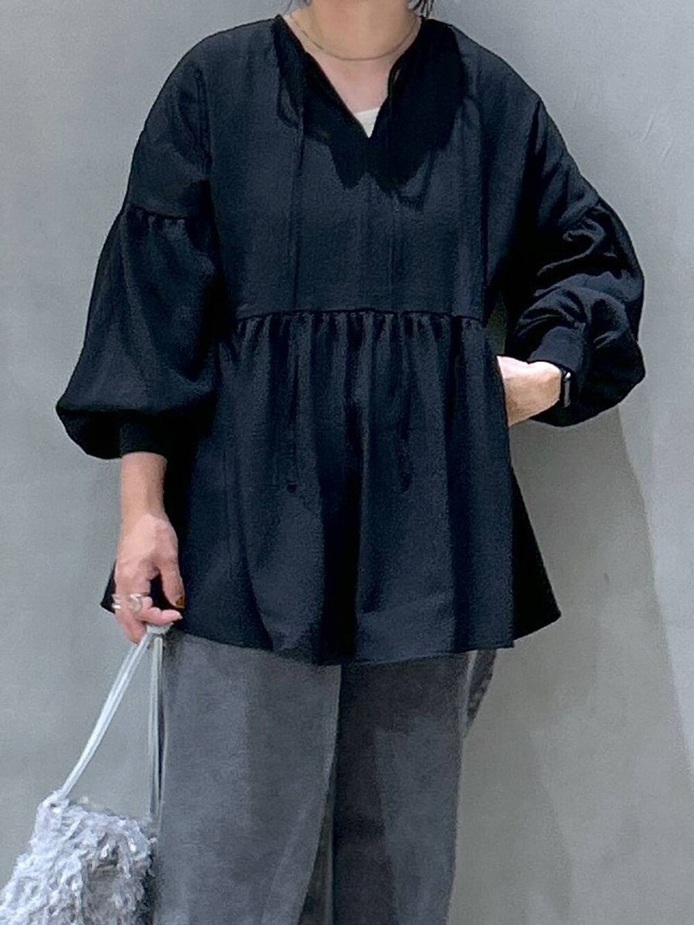 グレー系のスニーカー、ブラック系のデニムパンツ、グレー系のショルダーバッグを着用したレディースの夏コーディネートの3枚目の写真