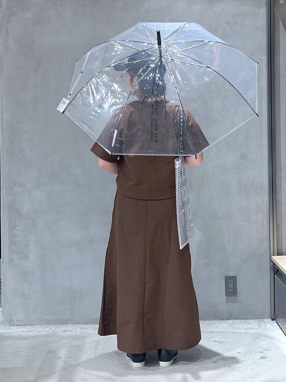 ブラック系のレインシューズ、ブラウン系のTシャツ/カットソー、ブラウン系のスカートを着用したレディースの夏コーディネートの6枚目の写真