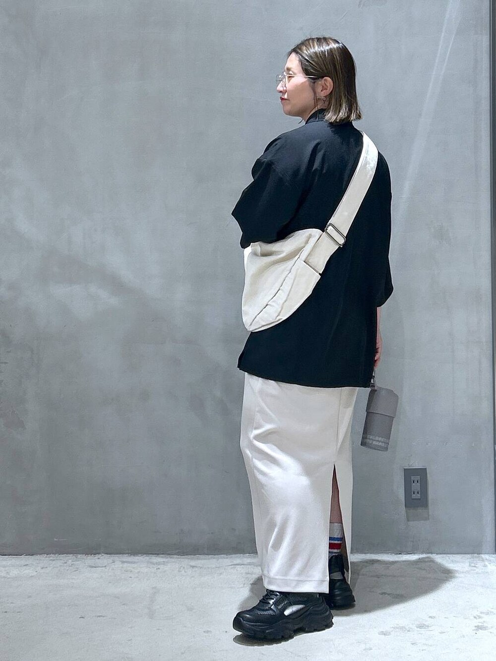 ベージュ系のショルダーバッグ、ブラック系のスニーカー、ベージュ系のスカートを着用したレディースの春コーディネートの2枚目の写真