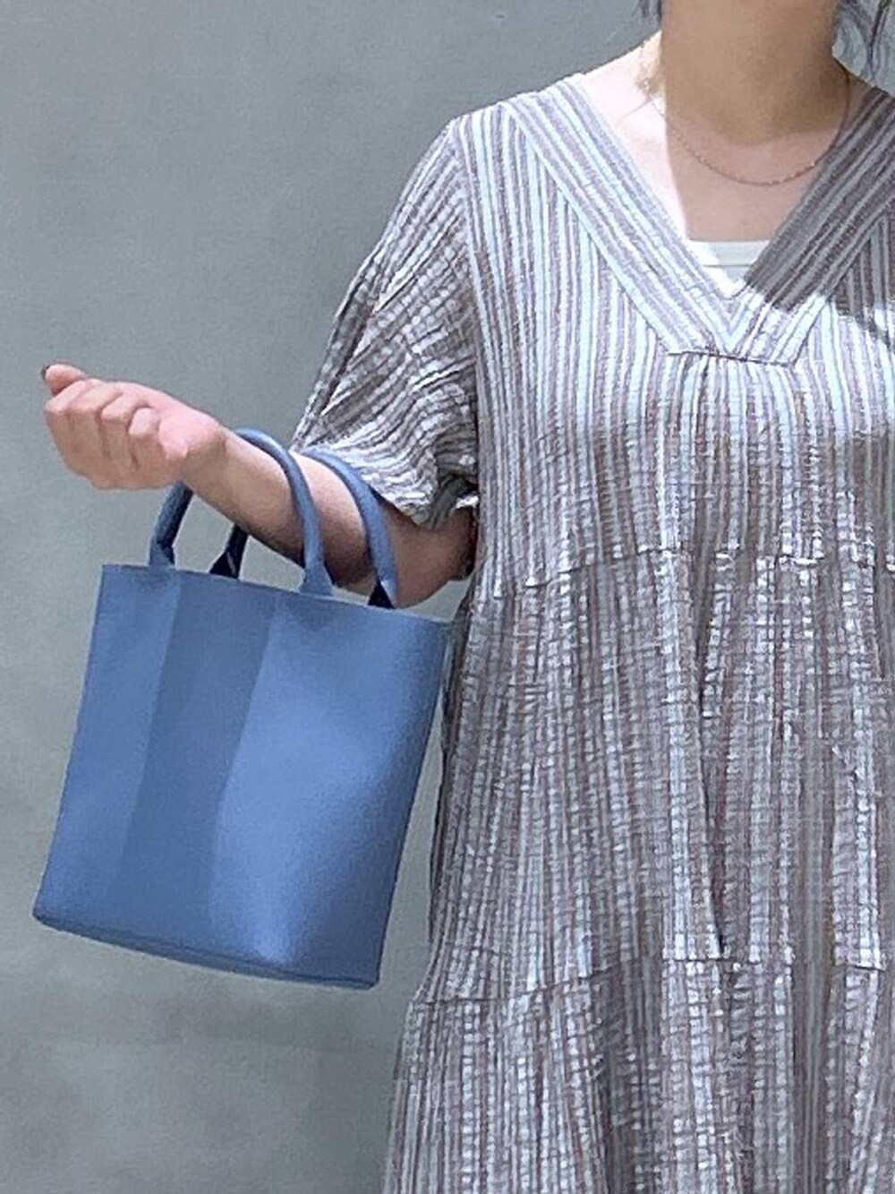 グレー系のワンピース、ブルー系のデニムパンツ、ブルー系のショルダーバッグを着用したレディースの夏コーディネートの4枚目の写真