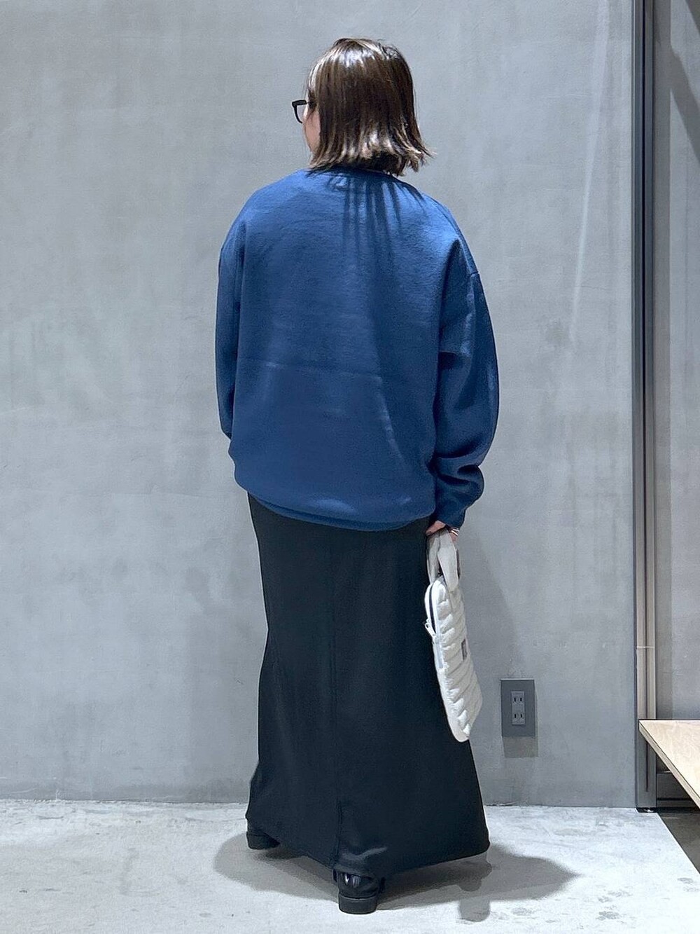 ブルー系のニット/セーター、ホワイト系のTシャツ/カットソー、ブラック系のスカートを着用したレディースの秋コーディネートの2枚目の写真