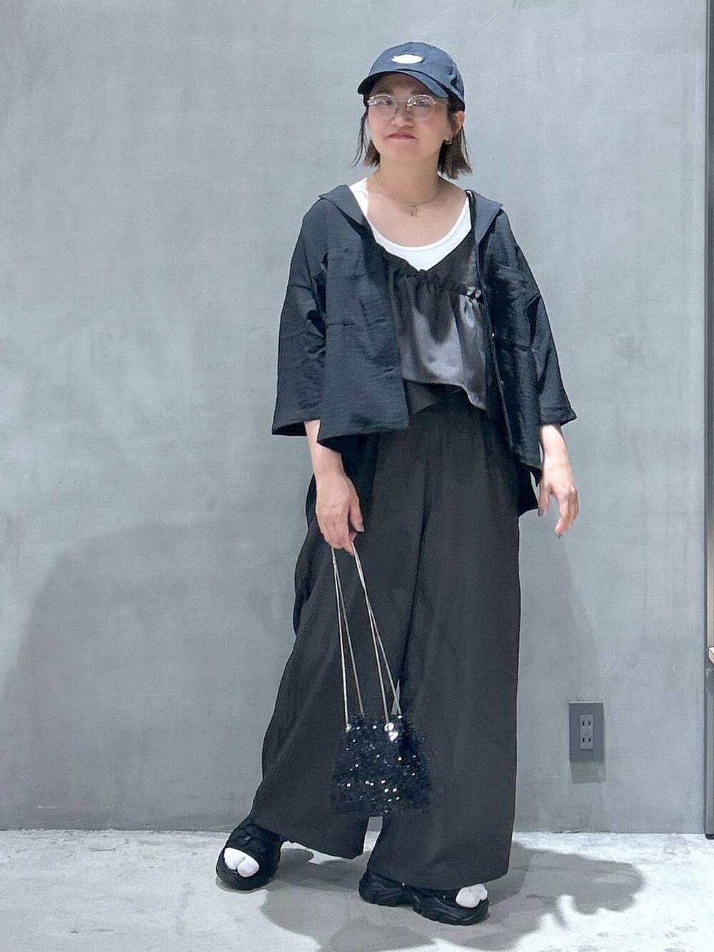 ブラック系のスニーカー、ホワイト系のタンクトップ、ブラック系のショルダーバッグを着用したレディースの春コーディネートの5枚目の写真