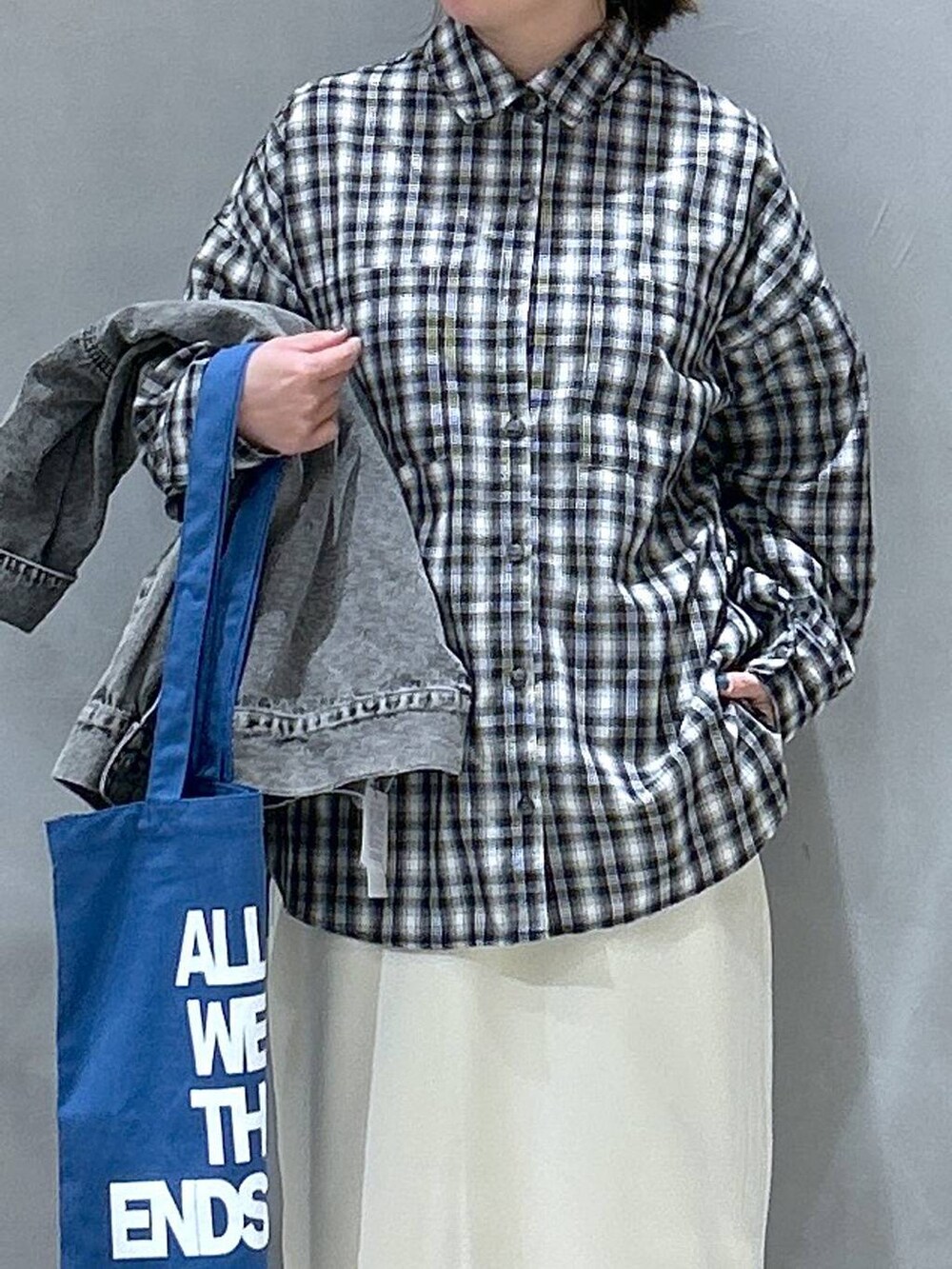 グレー系のスニーカー、ホワイト系のスカート、ブラック系のシャツ/ブラウスを着用したレディースの春コーディネートの3枚目の写真