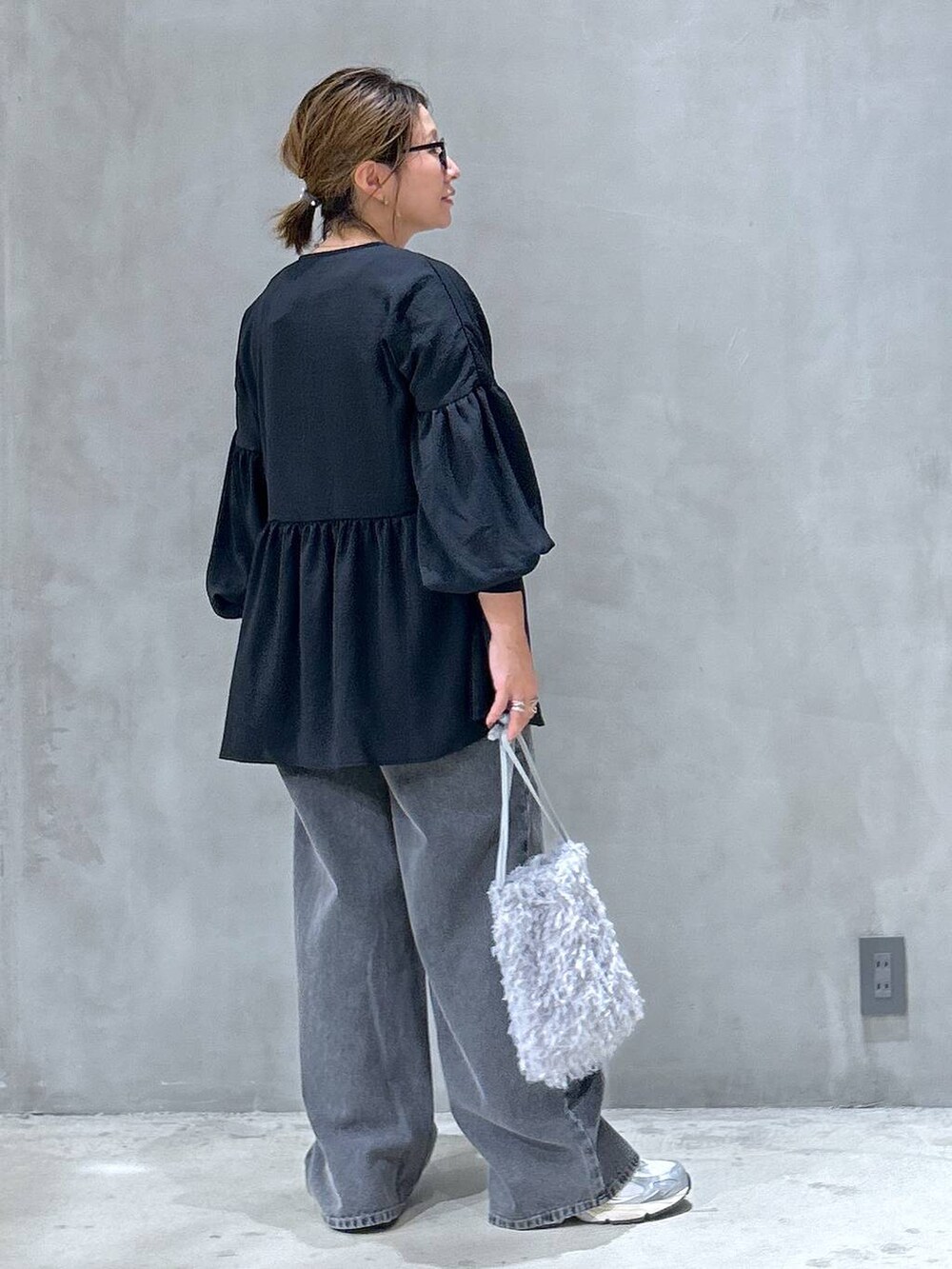 グレー系のスニーカー、ブラック系のデニムパンツ、グレー系のショルダーバッグを着用したレディースの夏コーディネートの2枚目の写真