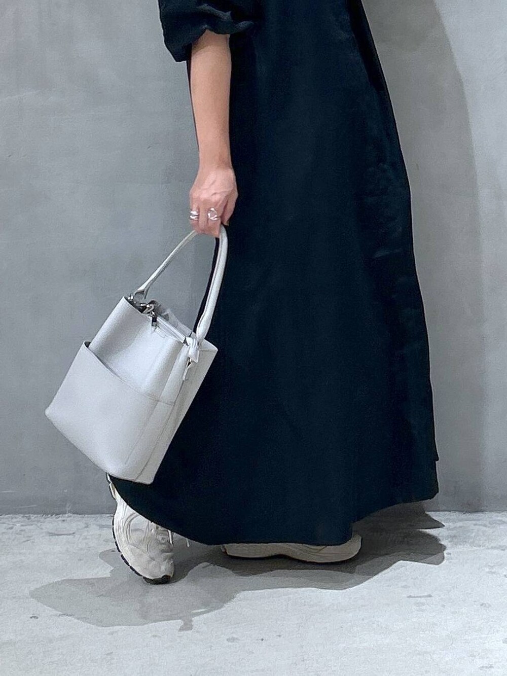 グレー系のショルダーバッグ、ブラック系のワンピース、グリーン系のキャップを着用したレディースの夏コーディネートの4枚目の写真