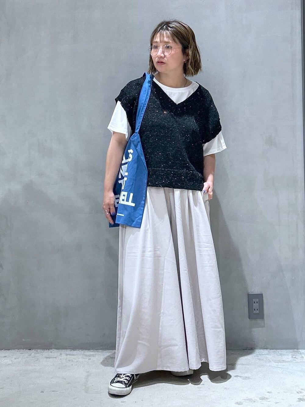 ブルー系のトートバッグ、ブラック系のベスト、グレー系のその他パンツを着用したレディースの夏コーディネートの7枚目の写真