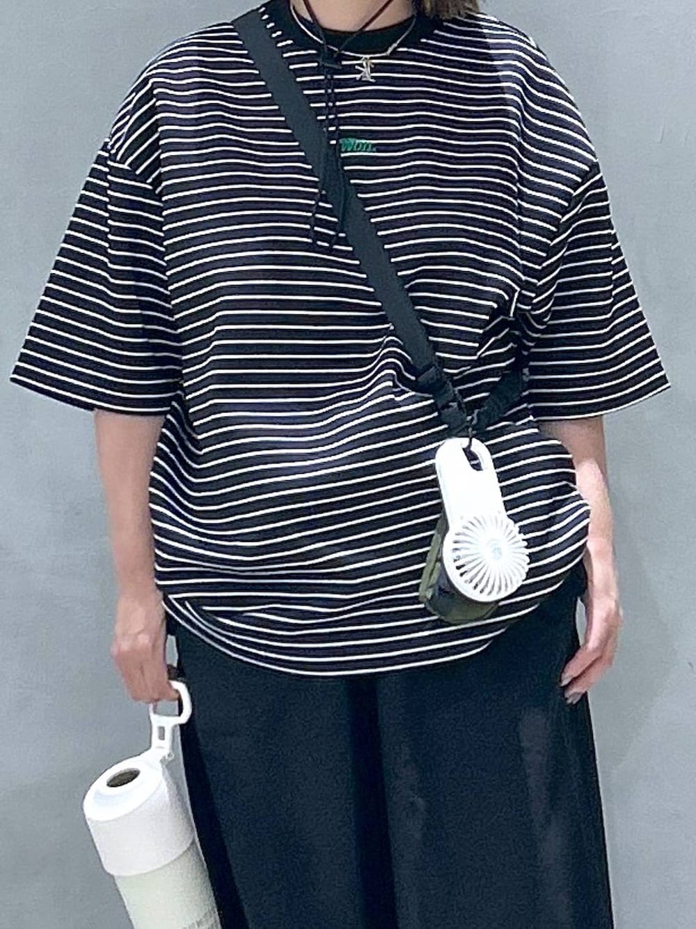 グリーン系のショルダーバッグ、ブラック系のスニーカー、ブラック系のスカートを着用したレディースの春コーディネートの3枚目の写真