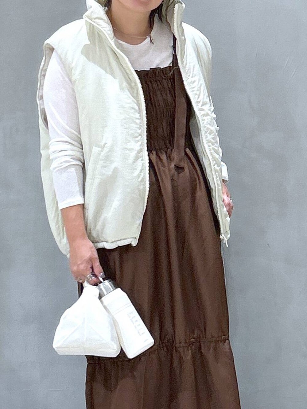 ホワイト系のスニーカー、ベージュ系のベスト、ブラウン系のワンピースを着用したレディースの秋コーディネートの2枚目の写真