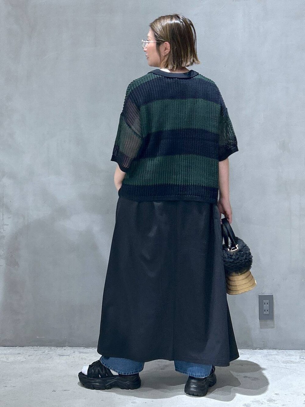 ブルー系のデニムパンツ、ベージュ系のショルダーバッグ、ブラック系のスニーカーを着用したレディースの春コーディネートの2枚目の写真