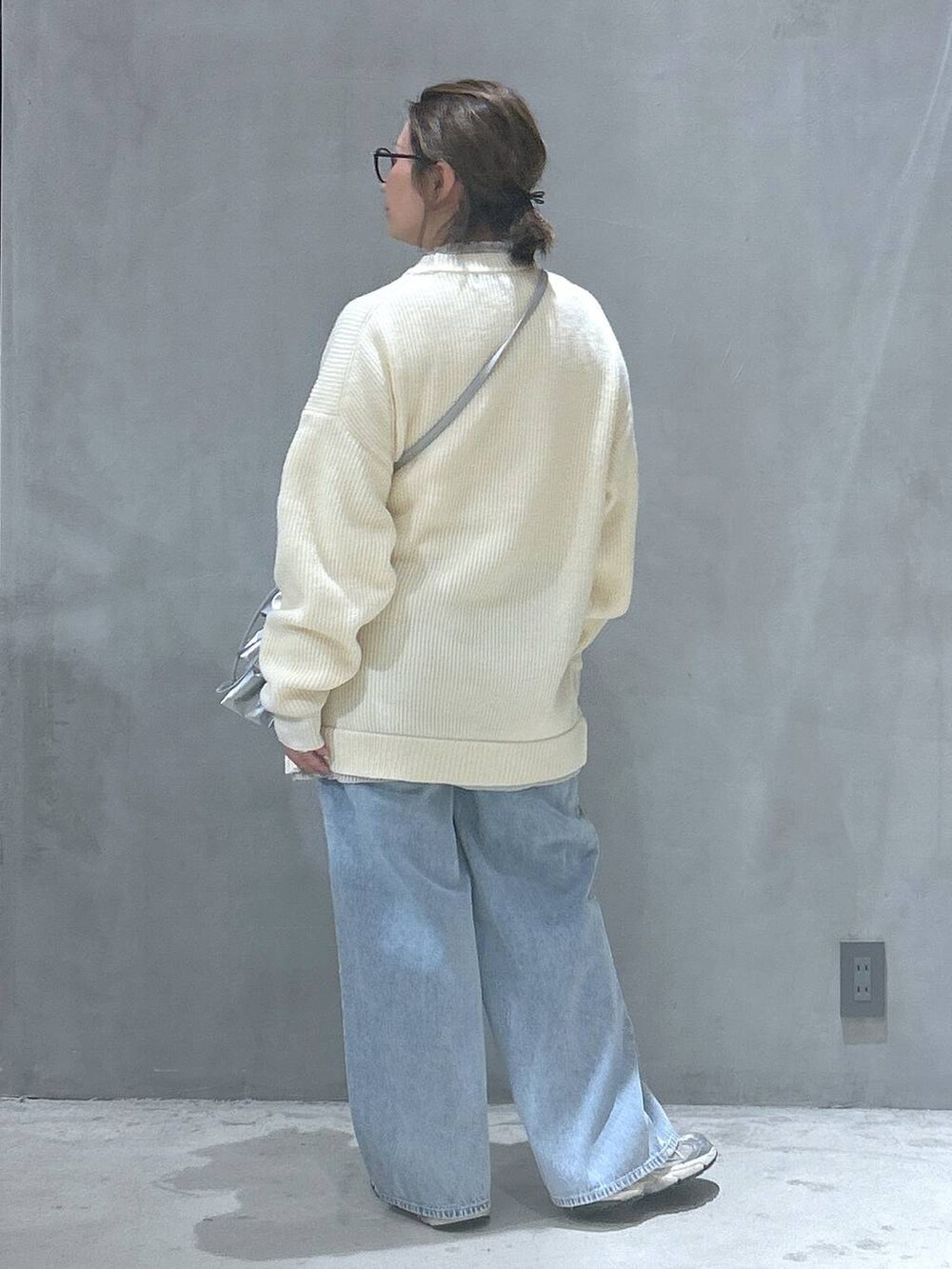 ブルー系のデニムパンツ、シルバー系のショルダーバッグ、ベージュ系のニット/セーターを着用したレディースの冬コーディネートの2枚目の写真