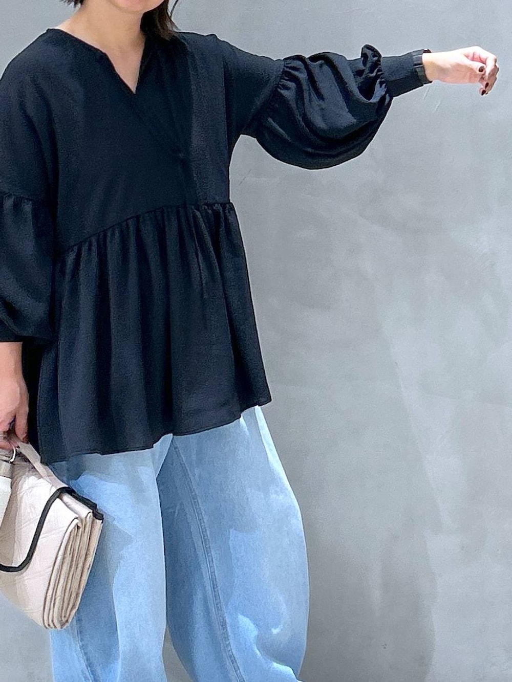 グレー系のスニーカー、ブルー系のデニムパンツ、ブラック系のチュニックを着用したレディースの秋コーディネートの5枚目の写真