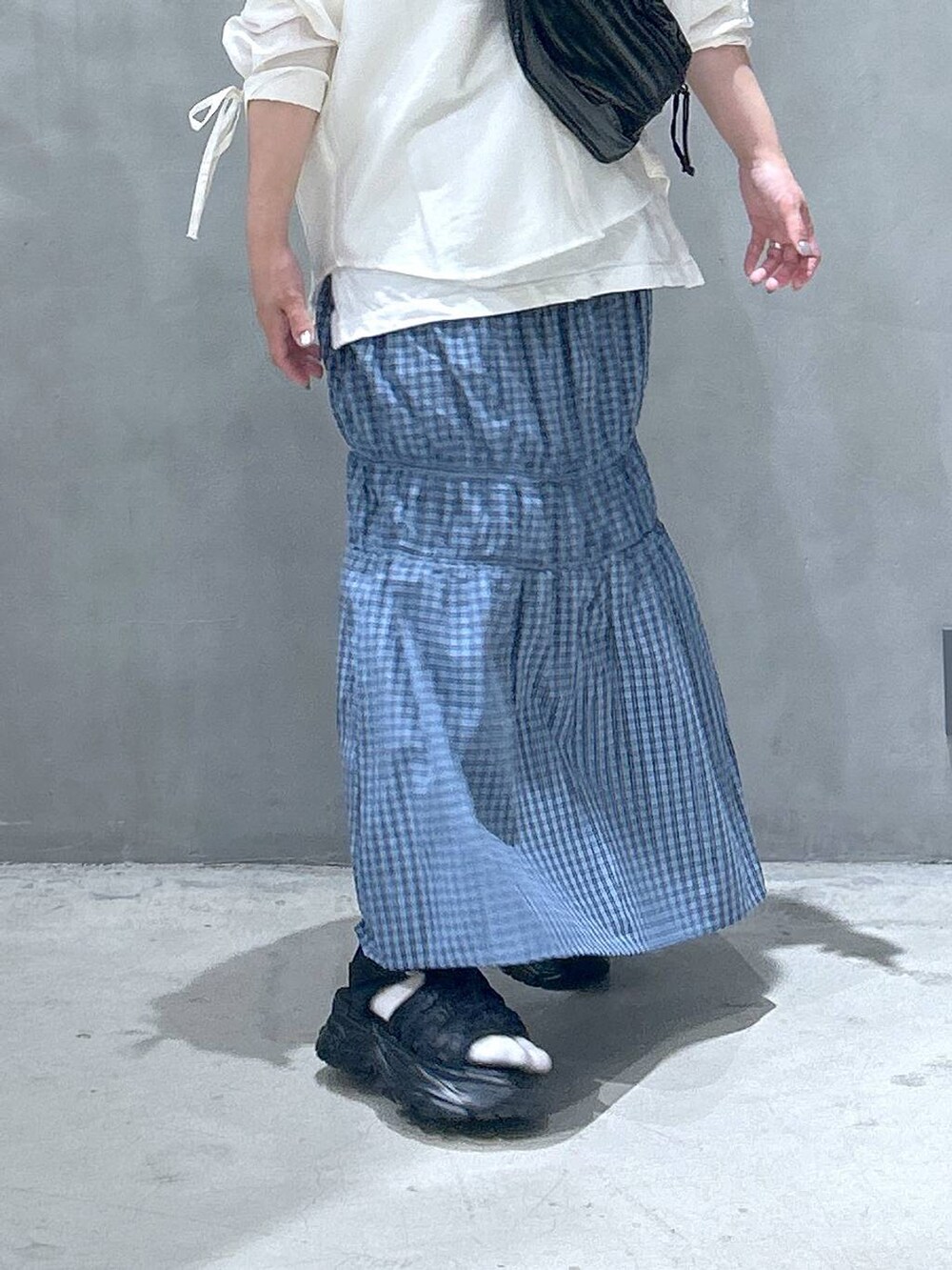 ブラック系のボディバッグ/ウエストポーチ、ブラック系のスニーカー、ホワイト系のシャツ/ブラウスを着用したレディースの春コーディネートの4枚目の写真