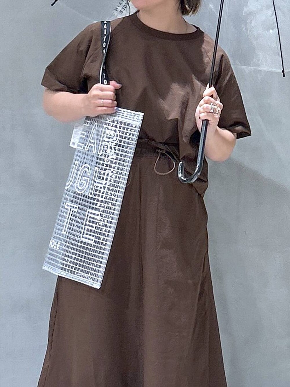 ブラック系のレインシューズ、ブラウン系のTシャツ/カットソー、ブラウン系のスカートを着用したレディースの夏コーディネートの3枚目の写真