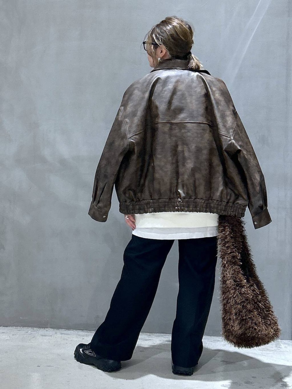 グレー系のスニーカー、ブラウン系のブルゾン、ブラウン系のショルダーバッグを着用したレディースの冬コーディネートの2枚目の写真