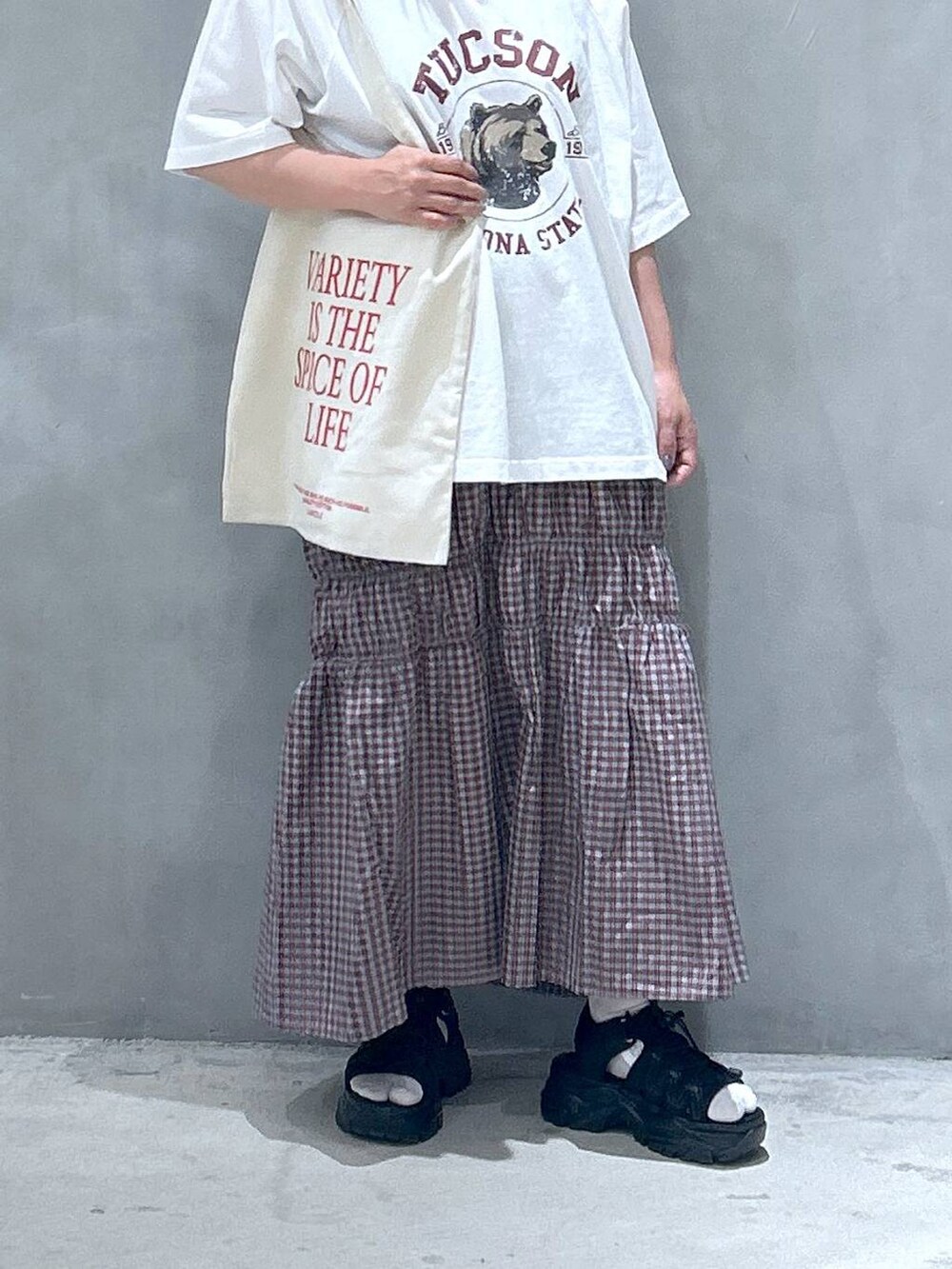 ブラック系のスニーカー、オレンジ系のスカート、ホワイト系のTシャツ/カットソーを着用したレディースの春コーディネートの3枚目の写真