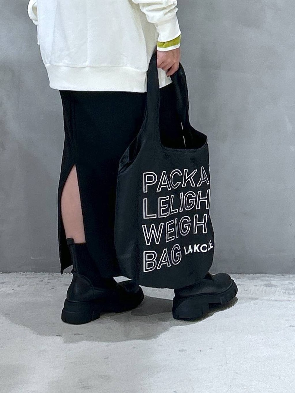 グリーン系のニット/セーター、ブラック系のブーツ、ブラック系のエコバッグ/サブバッグを着用したレディースの冬コーディネートの5枚目の写真