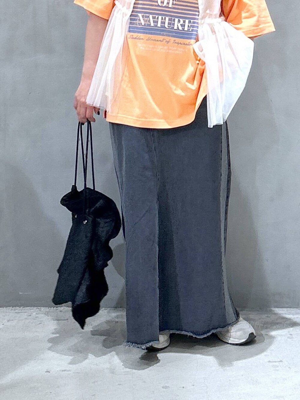 ブラック系のショルダーバッグ、ブラック系のデニムスカート、ベージュ系のベストを着用したレディースの春コーディネートの4枚目の写真