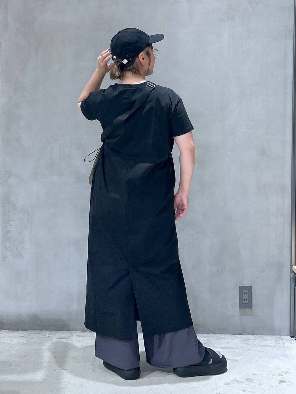 ブラック系のサンダル、グリーン系のショルダーバッグ、ブラック系のワンピースを着用したレディースの夏コーディネートの2枚目の写真