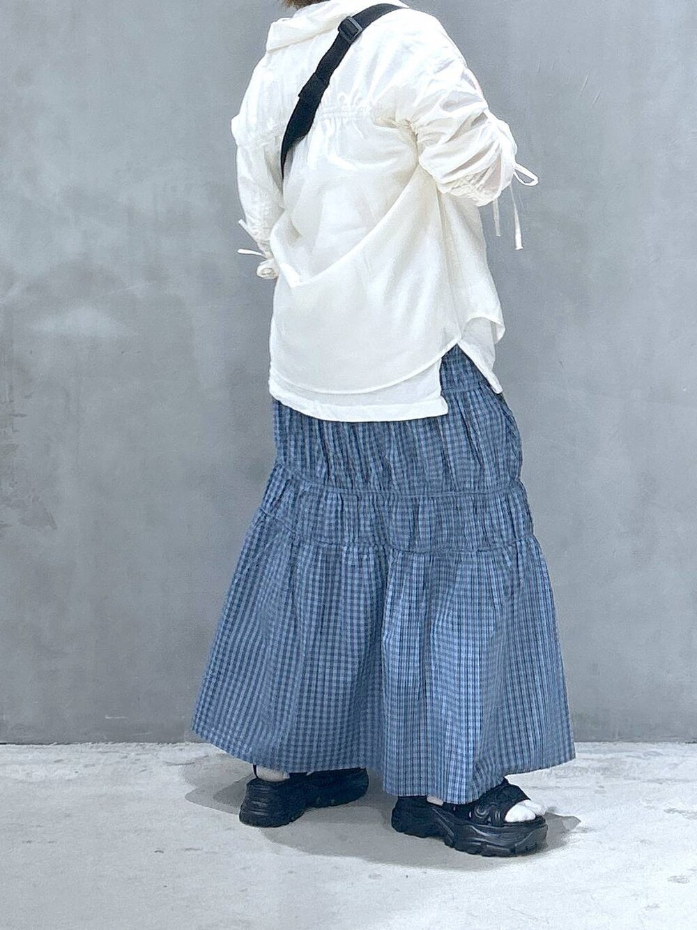 ブラック系のボディバッグ/ウエストポーチ、ブラック系のスニーカー、ホワイト系のシャツ/ブラウスを着用したレディースの春コーディネートの2枚目の写真