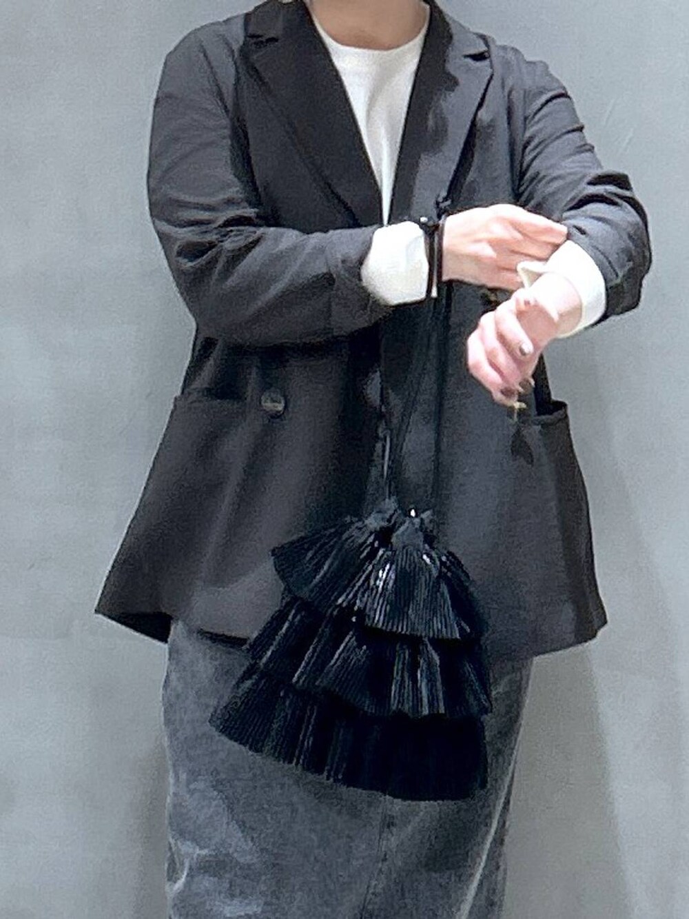 ブラック系のショルダーバッグ、ブラック系のジャンパースカート、グレー系のテーラードジャケットを着用したレディースの冬コーディネートの4枚目の写真