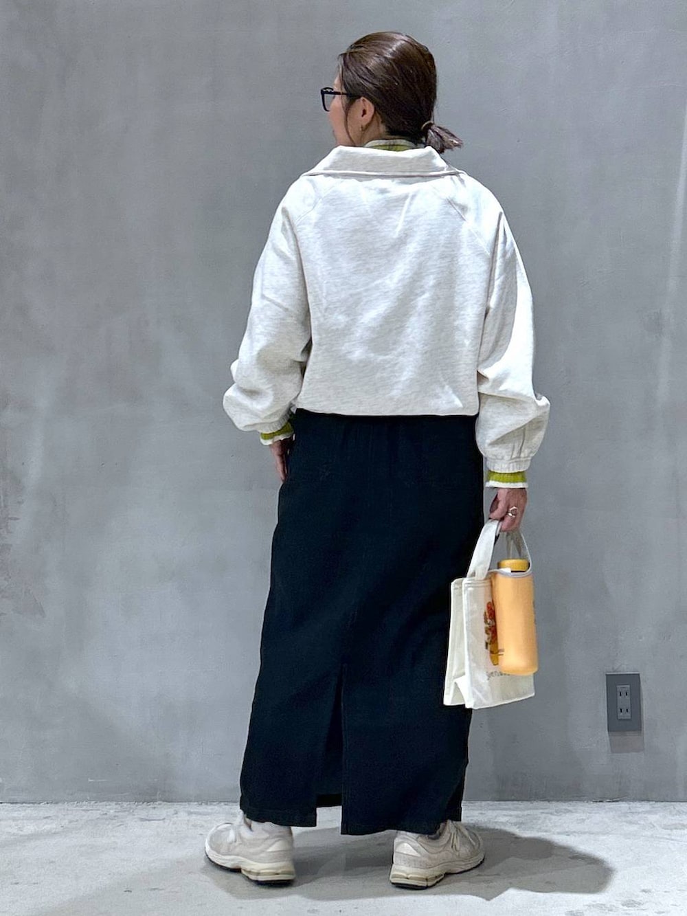 グレー系のジャンパースカート、ベージュ系のスウェット、グリーン系のニット/セーターを着用したレディースの秋コーディネートの2枚目の写真