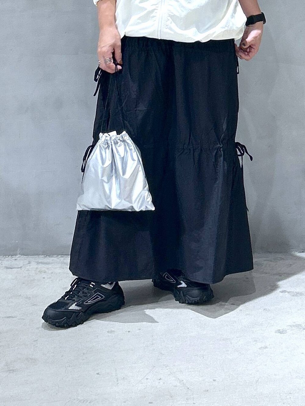 グレー系のスニーカー、ベージュ系のブルゾン、ブラック系のスカートを着用したレディースの秋コーディネートの4枚目の写真