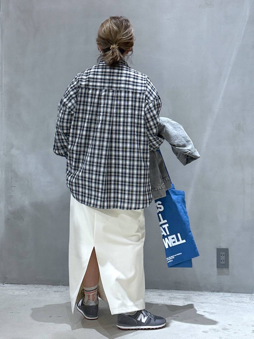 グレー系のスニーカー、ホワイト系のスカート、ブラック系のシャツ/ブラウスを着用したレディースの春コーディネートの2枚目の写真