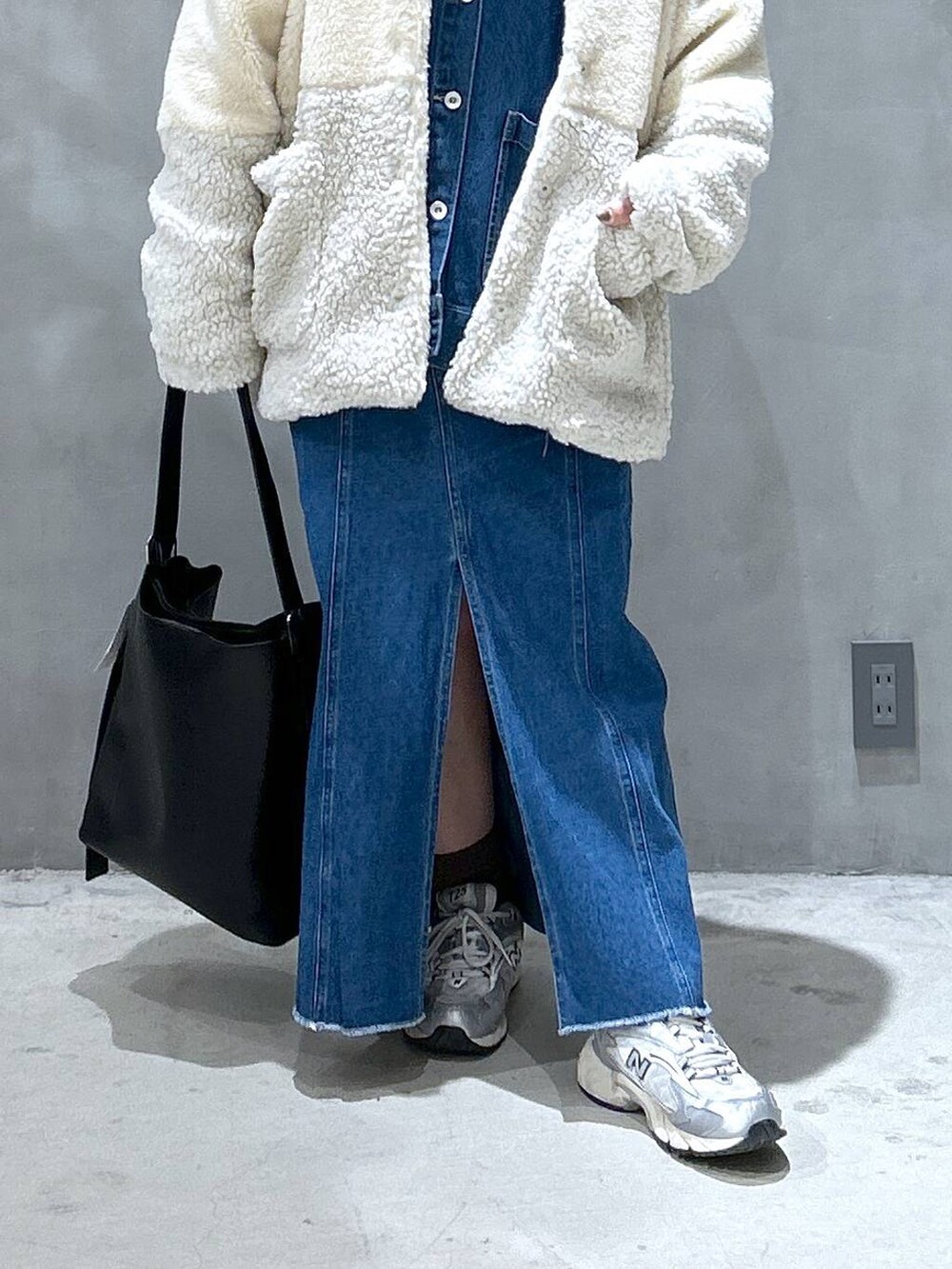 ベージュ系のブルゾン、ブルー系のデニムスカート、ブラック系のショルダーバッグを着用したレディースの冬コーディネートの4枚目の写真