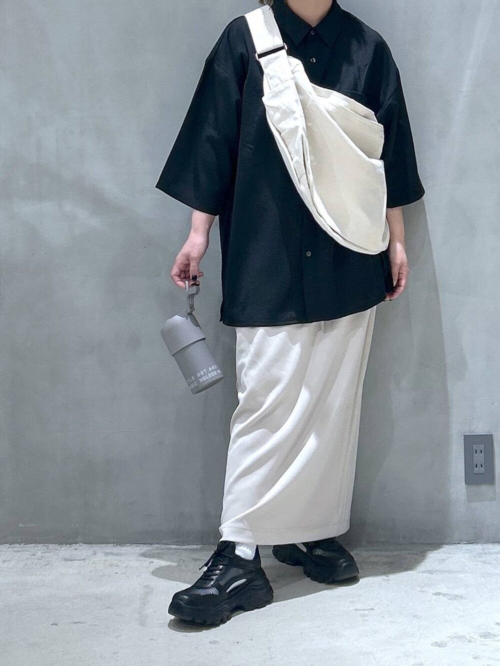 ベージュ系のショルダーバッグ、ブラック系のスニーカー、ベージュ系のスカートを着用したレディースの春コーディネートの6枚目の写真