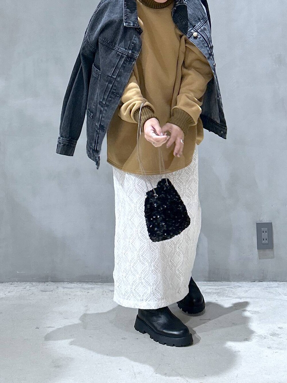 ブラック系のブーツ、ブラック系のデニムジャケット、ホワイト系のスカートを着用したレディースの秋コーディネートの4枚目の写真