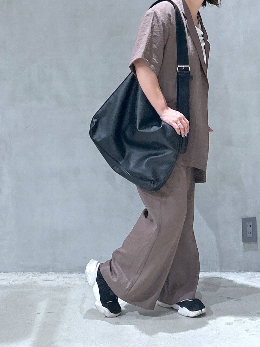 ブラック系のショルダーバッグ、ベージュ系のテーラードジャケット、ブラウン系のその他パンツを着用したレディースの夏コーディネートの6枚目の写真