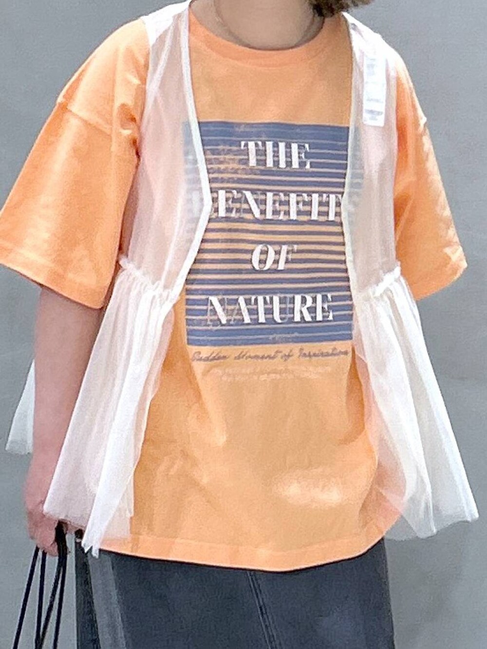 ブラック系のショルダーバッグ、ブラック系のデニムスカート、ベージュ系のベストを着用したレディースの春コーディネートの3枚目の写真