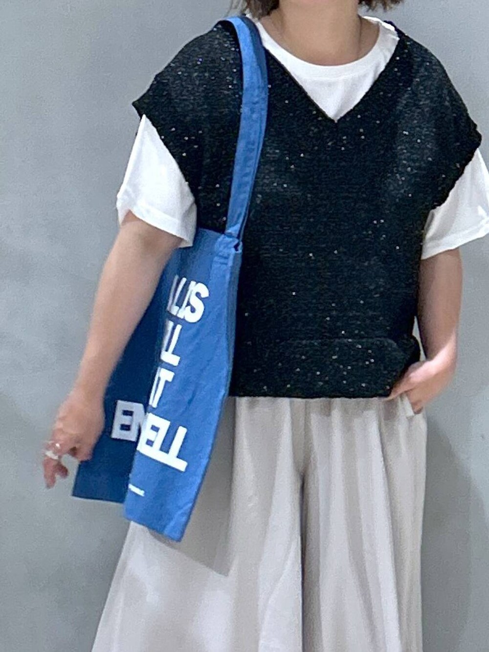 ブルー系のトートバッグ、ブラック系のベスト、グレー系のその他パンツを着用したレディースの夏コーディネートの3枚目の写真