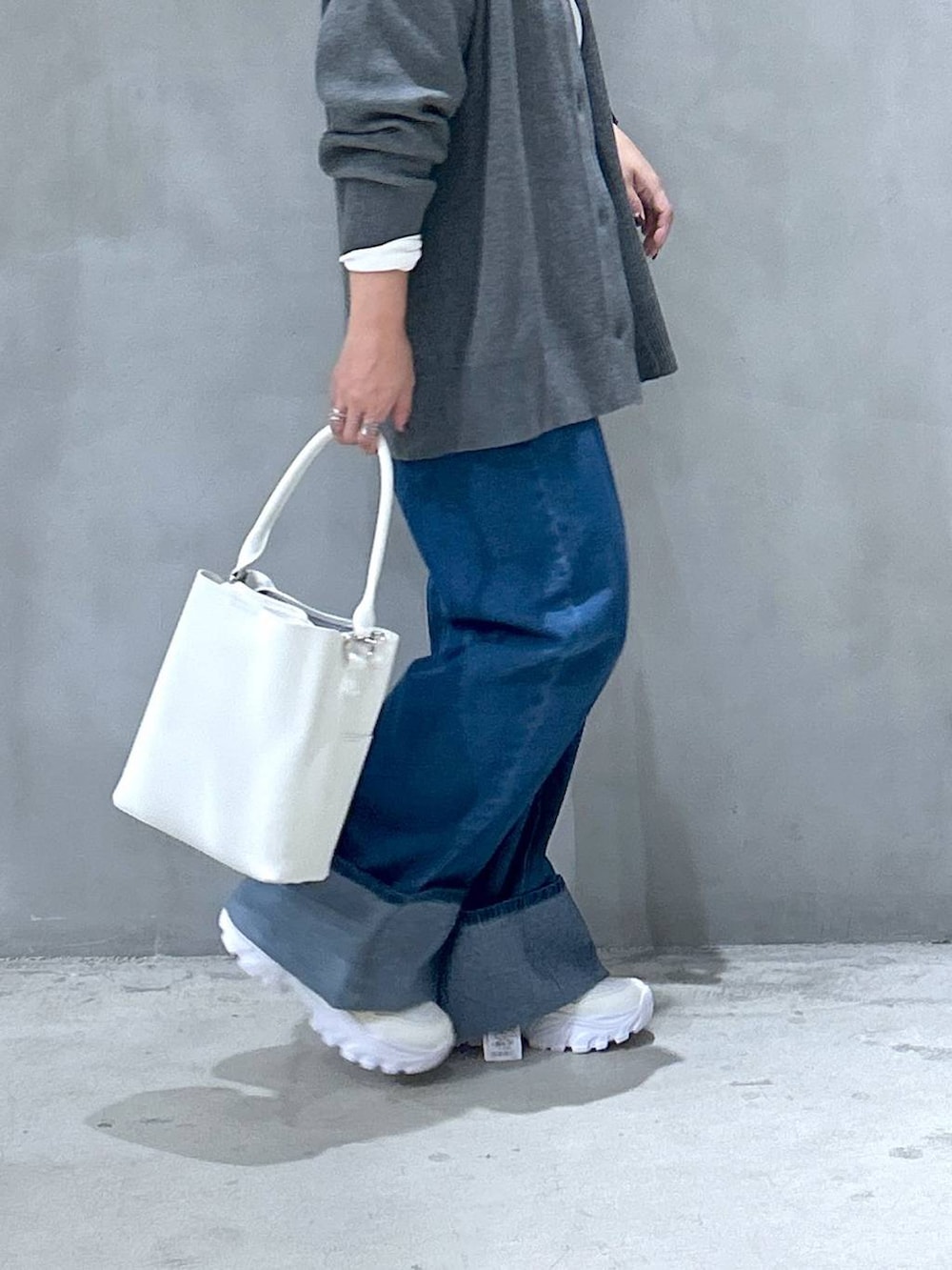 ホワイト系のスニーカー、ブルー系のデニムパンツ、ホワイト系のショルダーバッグを着用したレディースの秋コーディネートの4枚目の写真