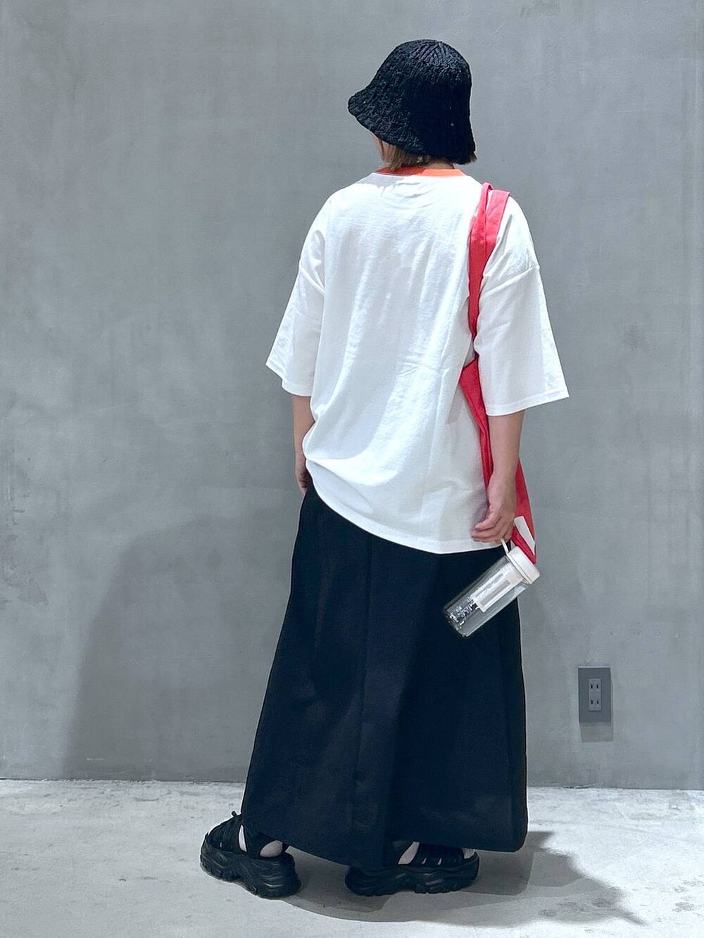 ブラック系のスニーカー、ブラック系のスカート、レッド系のTシャツ/カットソーを着用したレディースの春コーディネートの4枚目の写真