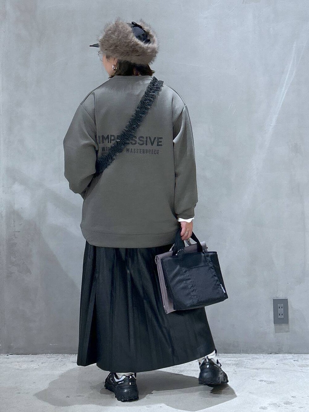 グレー系のスニーカー、ブラック系のスカート、グレー系のアウトドアグッズを着用したレディースの秋コーディネートの2枚目の写真