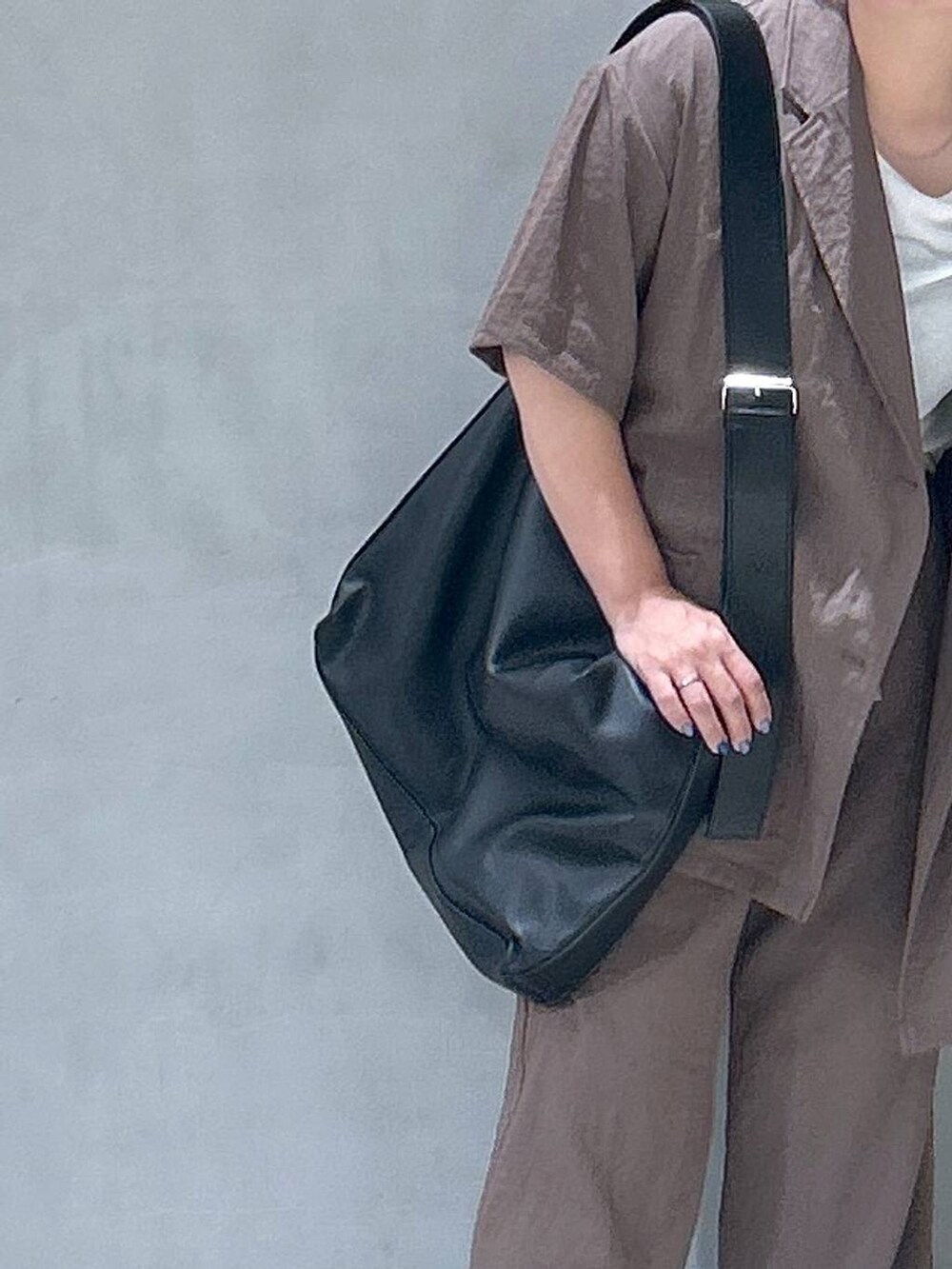 ブラック系のショルダーバッグ、ベージュ系のテーラードジャケット、ブラウン系のその他パンツを着用したレディースの夏コーディネートの3枚目の写真