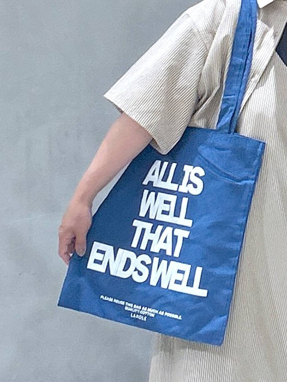 グレー系のスニーカー、ブルー系のトートバッグ、グレー系のTシャツ/カットソーを着用したレディースの春コーディネートの6枚目の写真