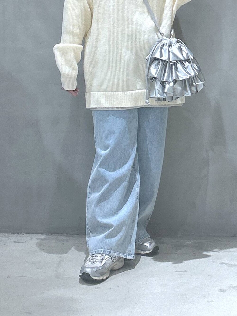 ブルー系のデニムパンツ、シルバー系のショルダーバッグ、ベージュ系のニット/セーターを着用したレディースの冬コーディネートの4枚目の写真