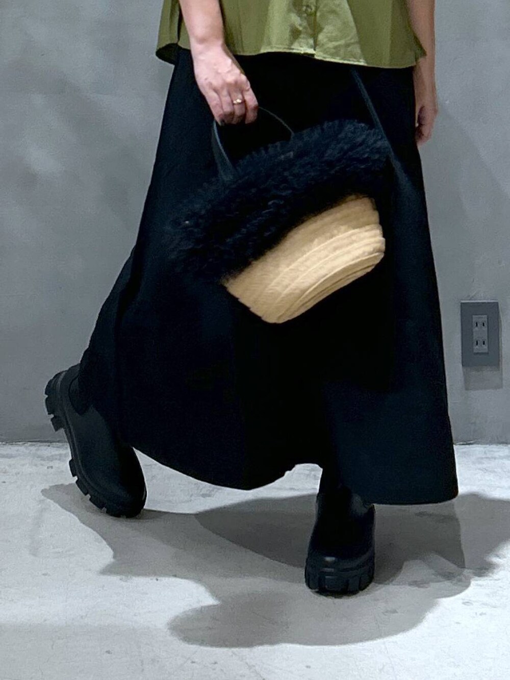 ブラック系のスカート、ベージュ系のショルダーバッグ、ブラック系のレインシューズを着用したレディースの夏コーディネートの4枚目の写真