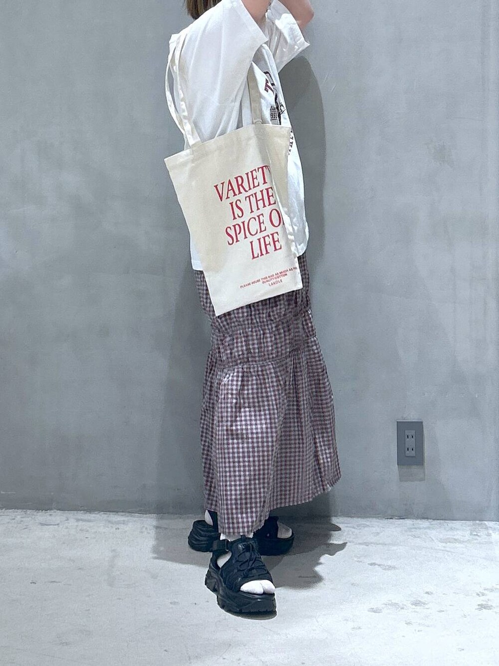ブラック系のスニーカー、オレンジ系のスカート、ホワイト系のTシャツ/カットソーを着用したレディースの春コーディネートの6枚目の写真
