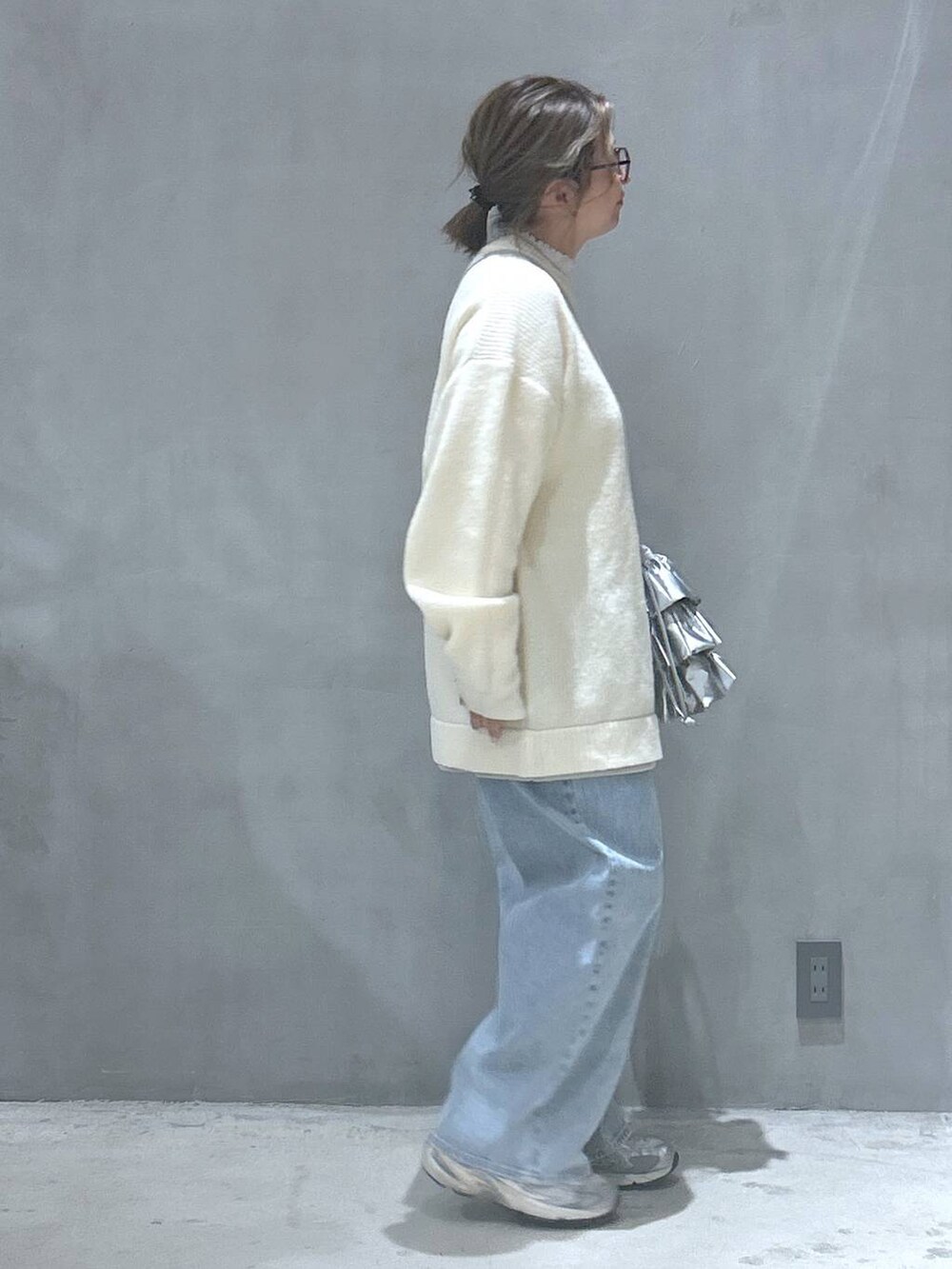 ブルー系のデニムパンツ、シルバー系のショルダーバッグ、ベージュ系のニット/セーターを着用したレディースの冬コーディネートの5枚目の写真