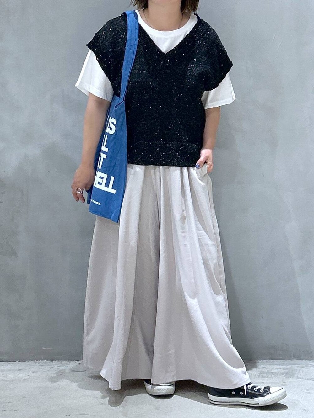 ブルー系のトートバッグ、ブラック系のベスト、グレー系のその他パンツを着用したレディースの夏コーディネートの4枚目の写真