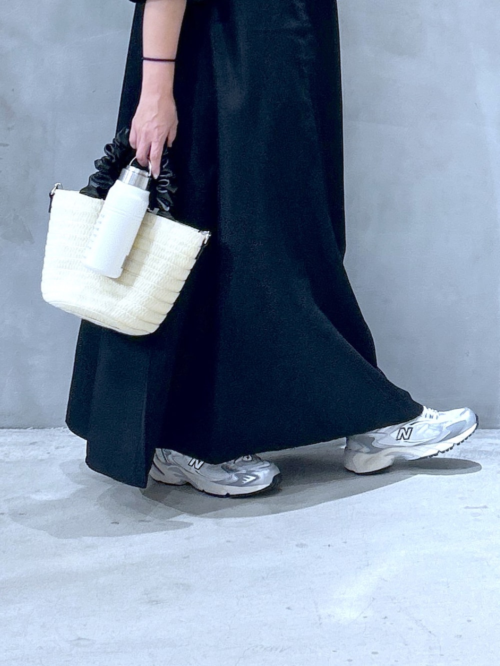 ブラック系のワンピース、グレー系のスニーカー、ホワイト系のショルダーバッグを着用したレディースの夏コーディネートの3枚目の写真
