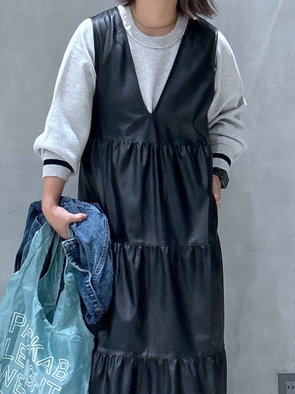 グレー系のスニーカー、ブラック系のワンピース、ブルー系のデニムジャケットを着用したレディースの秋コーディネートの3枚目の写真