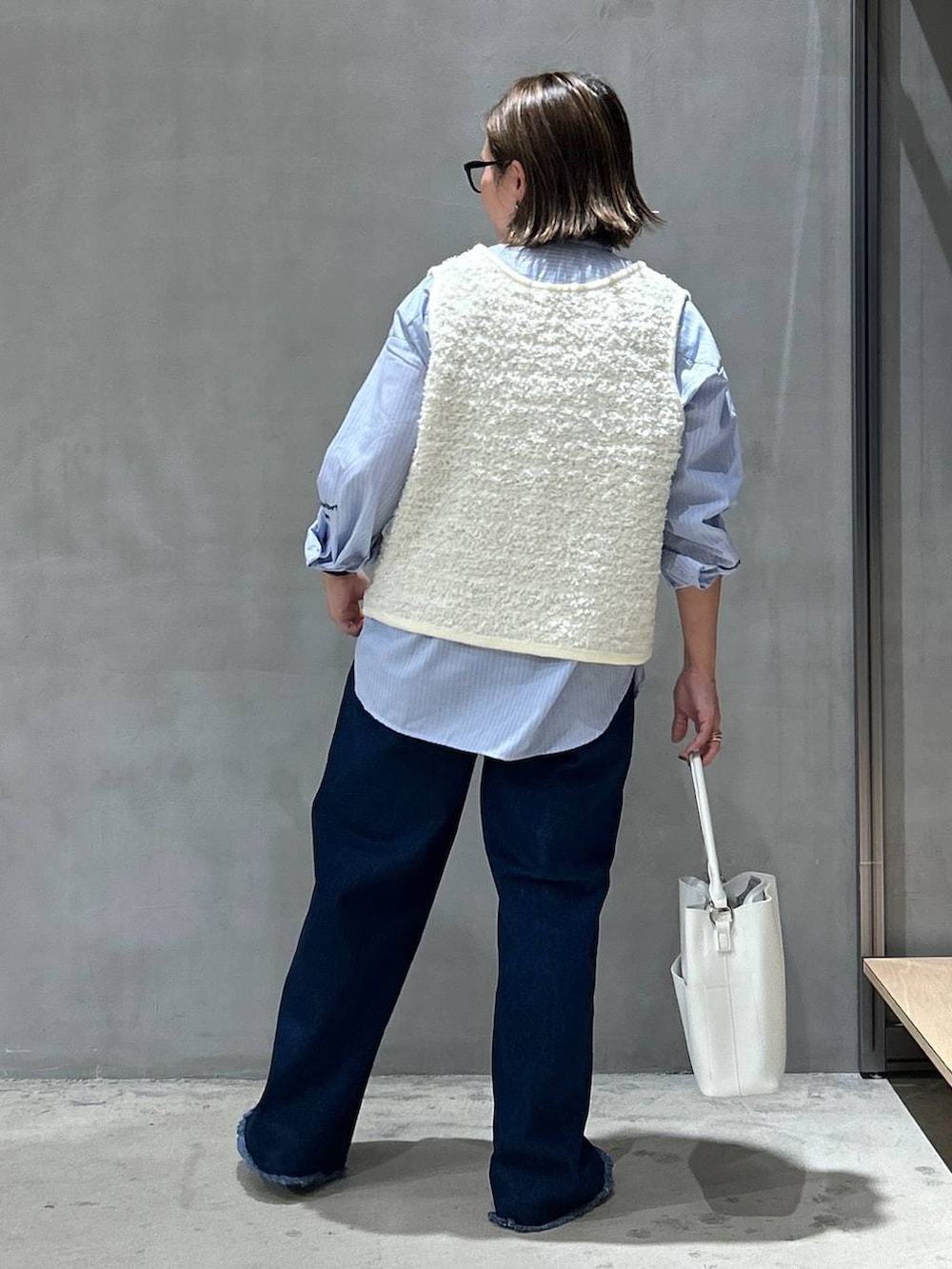 ブルー系のデニムパンツ、ブルー系のシャツ/ブラウス、ホワイト系のショルダーバッグを着用したレディースの秋コーディネートの2枚目の写真